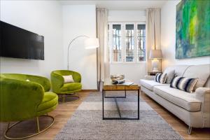 ein Wohnzimmer mit einem Sofa und zwei grünen Stühlen in der Unterkunft Genteel Home Recaredo in Sevilla