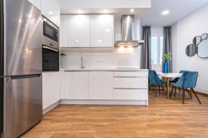 een keuken met witte kasten en een tafel met stoelen bij Genteel Home Recaredo in Sevilla +102 foto's