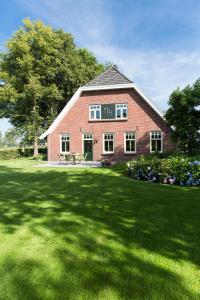 une grande maison en briques rouges avec une grande cour dans l'établissement Vakantiewoning De Beiert, à Delden