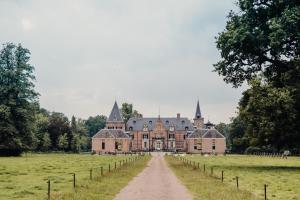 uma casa grande num campo com uma estrada de terra em Vakantiewoning De Beiert em Delden