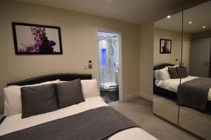 1 dormitorio con 2 camas y espejo en Northside Apartments Ealing, en Londres