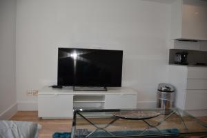 ein Wohnzimmer mit einem TV auf einem weißen Stand in der Unterkunft Northside Apartments Ealing in London