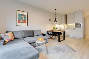 a living room with a gray couch and a kitchen at 4 Seasons Jelitkowo + Beach in Gdańsk