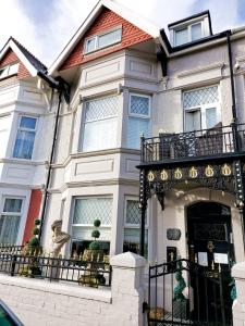 a white house with a porch and a balcony at Olivia House in Porthcawl