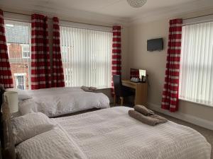 two beds in a bedroom with red and white curtains at The Ball Alley in Stanley