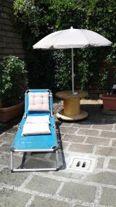 a blue chair under an umbrella next to a table at La Casa di Muro in Oriolo Romano