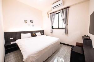 een slaapkamer met een groot wit bed en een raam bij 樂洋洋民宿 in Magong