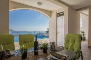 a dining room with a table and green chairs at Luxury Apartment Goja with private pool and Jacuzzi near Dubrovnik in Ivanica