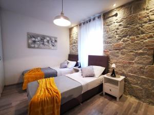 two beds in a room with a stone wall at Apartment Herc in Split