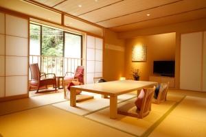 a living room with a table and chairs at Yuraku Kinosaki Spa & Gardens in Toyooka