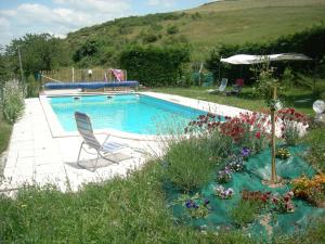een zwembad met een stoel en bloemen in een tuin bij Gites "Le Bret" in Saint-Sylvestre