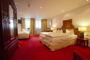 a hotel room with two beds and a red carpet at Historik Hotel Goldener Hirsch Rothenburg in Rothenburg ob der Tauber