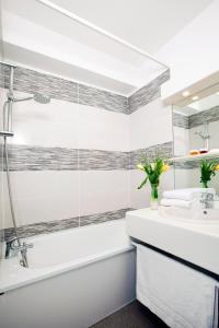 La salle de bains est pourvue d'une baignoire, d'un lavabo et d'un miroir. dans l'établissement Séjours & Affaires Annecy Le Pont Neuf, à Annecy