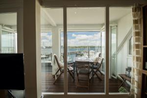 einen Balkon mit Tisch und Stühlen und Blick auf ein Boot in der Unterkunft fewo1846 - Baltic Lodge - komfortable Maisonettewohnung mit 3 Schlafzimmern, Balkon und Blick auf die Marina Sonwik in Flensburg