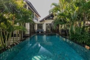 a swimming pool in front of a house with palm trees at Top 5 star BALI RESORT VILLA KARUNA 4 bedrooms in Ungasan