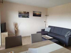 ein Wohnzimmer mit einem blauen Sofa und einem Tisch in der Unterkunft Fewo-Eifel-Morsbach in Schleiden