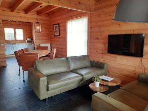 ein Wohnzimmer mit einem Sofa, einem TV und einem Tisch in der Unterkunft Holiday Park Dennenbos in Oostkapelle