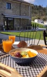 un tazón de comida sentado en una mesa con zumo de naranja en Lugar das Marías en Jove