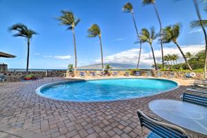 una piscina con palmeras, mesa y sillas en Ocean-View Kihei Condo with Lanai Steps to Beach!, en Kihei