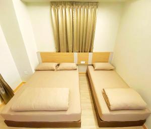 two beds in a small room with a curtain at Amadel Residence 爱媄德民宿 16 in Malacca