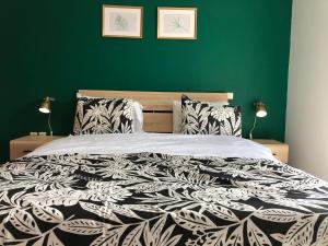 a green bedroom with a bed with a black and white comforter at Anastasias house near Athens airport in Spata
