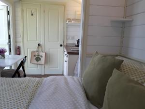 a bedroom with a bed and a table and a kitchen at Romantic Shepherds Hut, Kenilworth in Kenilworth