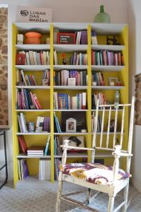 uma estante de livros amarela com uma cadeira em frente em Lugar das Marías em Jove