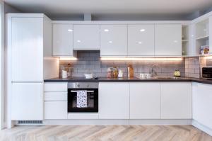 a kitchen with white cabinets and an oven at Eyre Square Galway Central Self Catering in Galway