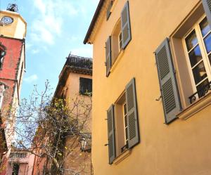 un bâtiment avec des volets verts et une tour d'horloge dans l'établissement Beau Clocher, à Saint-Tropez
