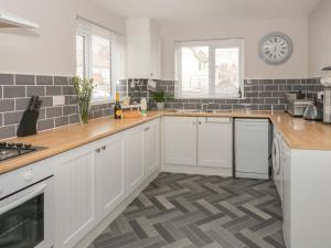 a kitchen with white cabinets and wooden counter tops at 31 Lloyd Street West in Llandudno