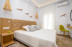 a bedroom with a white bed and a green chair at Beach Connection Naxos town in Naxos Chora