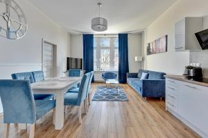 a kitchen and living room with a table and blue chairs at Blue Mandarin Apartments III Haffnera in Sopot