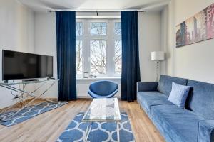 uma sala de estar com um sofá azul e uma televisão em Blue Mandarin Apartments III Haffnera em Sopot