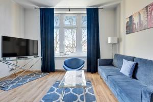 a living room with a blue couch and a tv at Blue Mandarin Apartments III Haffnera in Sopot