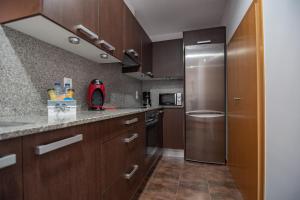 eine Küche mit Holzschränken und einem Edelstahlkühlschrank in der Unterkunft Attic Deltarelax in Deltebre