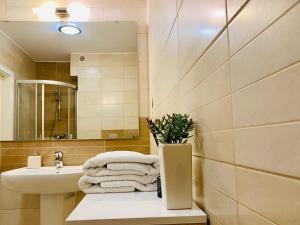 a bathroom with a sink and a mirror and towels at Apartamenty Maritimo in Kołobrzeg