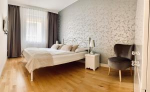 a white bedroom with a bed and a chair at Apartamenty Maritimo in Kołobrzeg