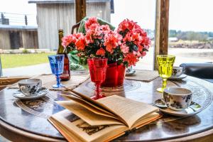 an open book on a table with flowers and glasses at Apartamenti Vējdzirnavas in Ventspils