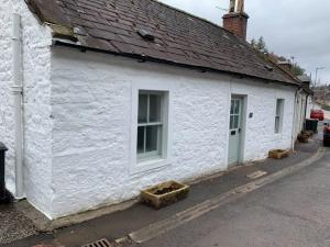 un bâtiment blanc avec une fenêtre et un toit dans l'établissement Boggle Dyke Cottage, à Thornhill