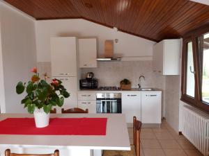 eine Küche mit weißen Schränken und einem Tisch mit einer Topfpflanze in der Unterkunft Bnbook Casa dei Peschi - Lago di Monate in Cadrezzate