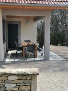 eine Terrasse mit einem Holztisch und Stühlen in der Unterkunft La Maison du Colombier in Le Fied