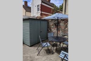 patio ze stołem, krzesłami i parasolem w obiekcie Hidden Gem in the Bay 10 Mins from WMC w Cardiff