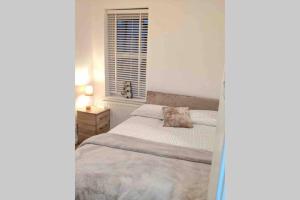 a white bedroom with a bed and a window at Hidden Gem in the Bay 10 Mins from WMC in Cardiff