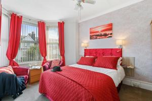 a bedroom with a red bed and red curtains at The Ashleigh in Paignton