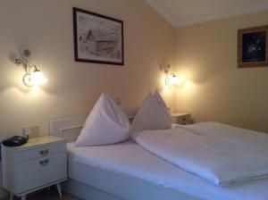 Schlafzimmer mit einem Bett mit weißer Bettwäsche und Kissen in der Unterkunft Ferienhaus Emberger in Wagrain