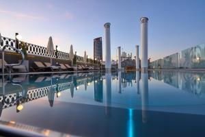 a swimming pool with chairs and a city in the background at Monte Triana in Seville