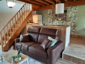 a brown leather couch in a living room with stairs at La Grange d' Angel in Châtillon-sur-Marne +8 photos