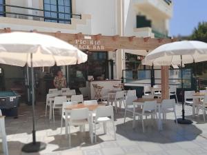 a restaurant with tables and white chairs and umbrellas at Dunas 107 in Alvor