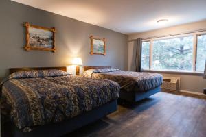 Cette chambre comprend 2 lits et une fenêtre. dans l'établissement Rimrock Lodge LLC, à Thompson Falls