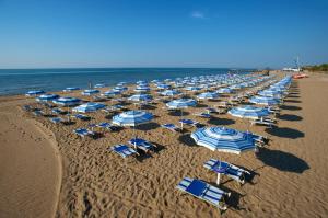 ein paar Stühle und Sonnenschirme am Strand in der Unterkunft Europa Camping Village in Cavallino-Treporti